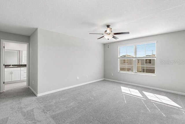 carpeted spare room with ceiling fan and a textured ceiling