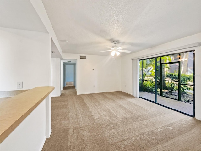 spare room featuring light colored carpet, ceiling fan, and a textured ceiling