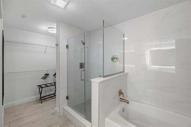 bathroom featuring a textured ceiling and shower with separate bathtub