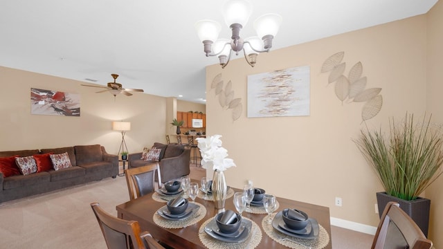 carpeted dining area with ceiling fan with notable chandelier