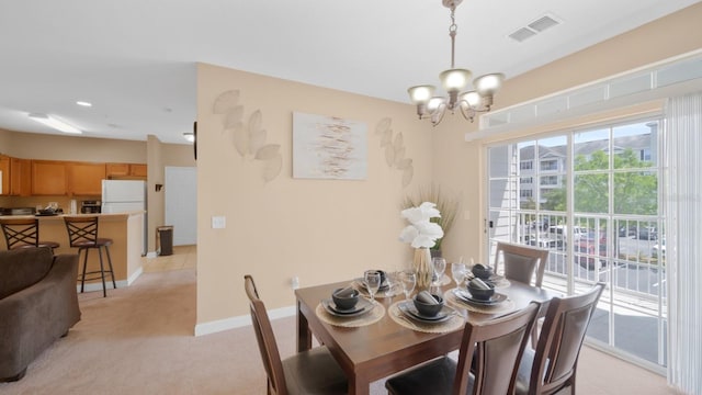 dining space featuring light carpet and an inviting chandelier