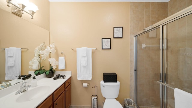 bathroom featuring a shower with shower door, vanity, and toilet