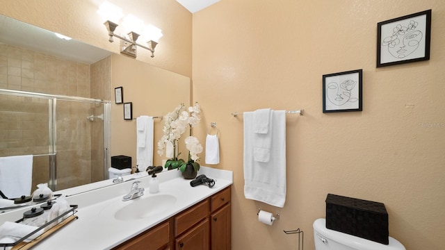 bathroom with vanity, a shower with door, and toilet