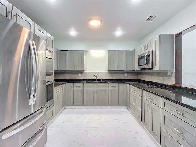 kitchen with gray cabinetry, stainless steel appliances, light tile floors, sink, and tasteful backsplash