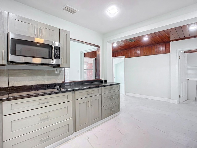 kitchen with wooden ceiling, gray cabinets, black gas stovetop, and backsplash