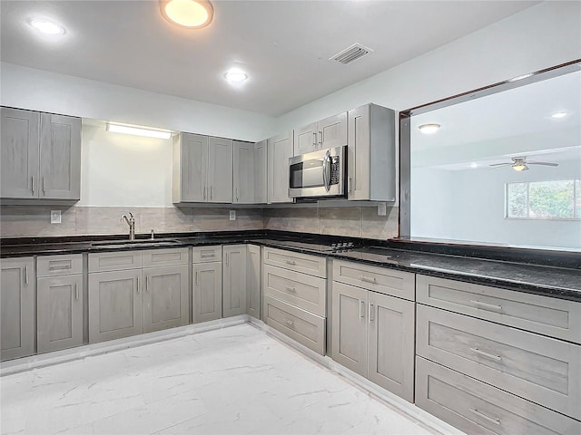 kitchen with tasteful backsplash, gray cabinets, ceiling fan, and light tile flooring