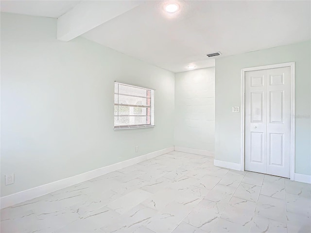 tiled spare room with beamed ceiling