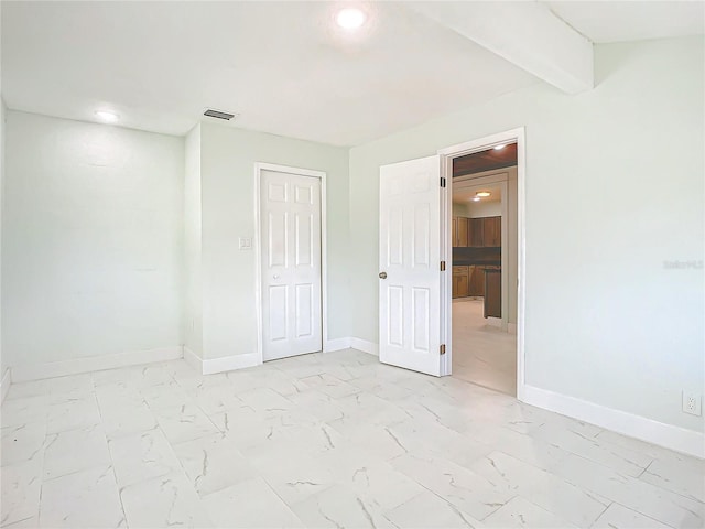 unfurnished bedroom with beam ceiling, a closet, and light tile flooring