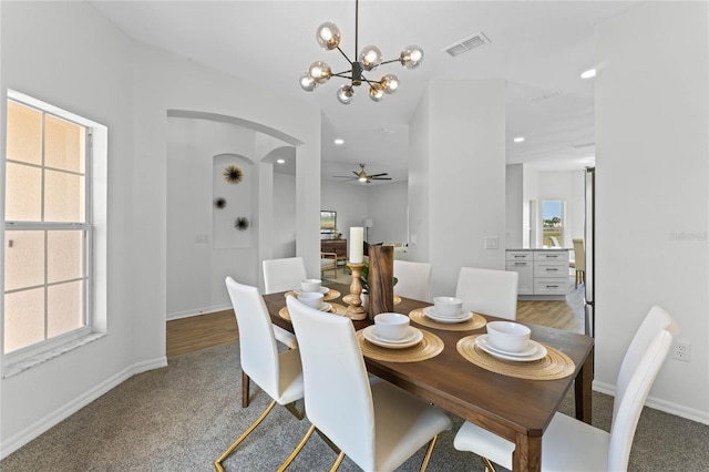 carpeted dining area featuring ceiling fan with notable chandelier