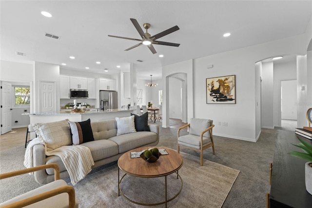 living room featuring ceiling fan with notable chandelier and carpet floors