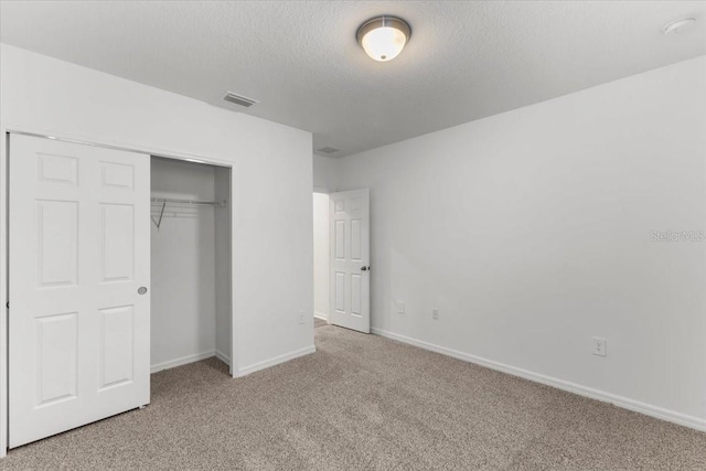 unfurnished bedroom with light carpet, a textured ceiling, and a closet