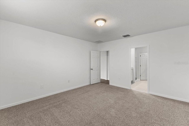 carpeted empty room featuring a textured ceiling