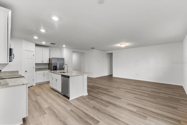 kitchen with an island with sink, white cabinetry, light hardwood / wood-style flooring, sink, and stainless steel appliances