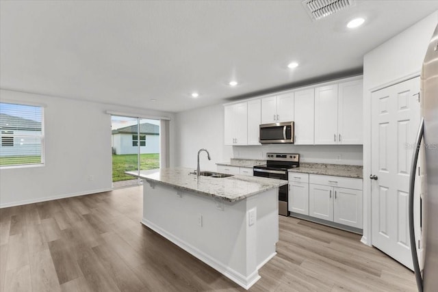 kitchen featuring appliances with stainless steel finishes, sink, white cabinets, light hardwood / wood-style flooring, and a kitchen island with sink