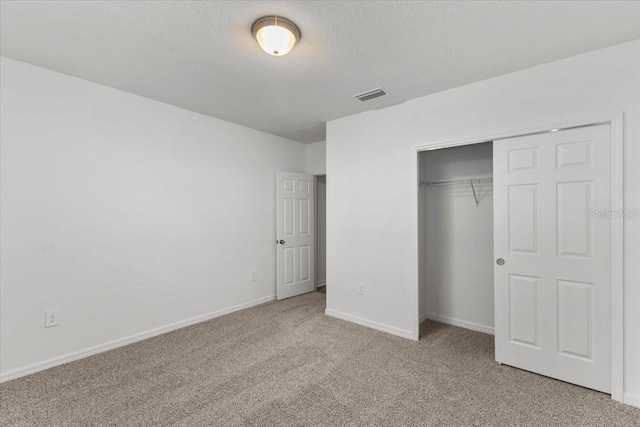 unfurnished bedroom featuring light carpet, a textured ceiling, and a closet