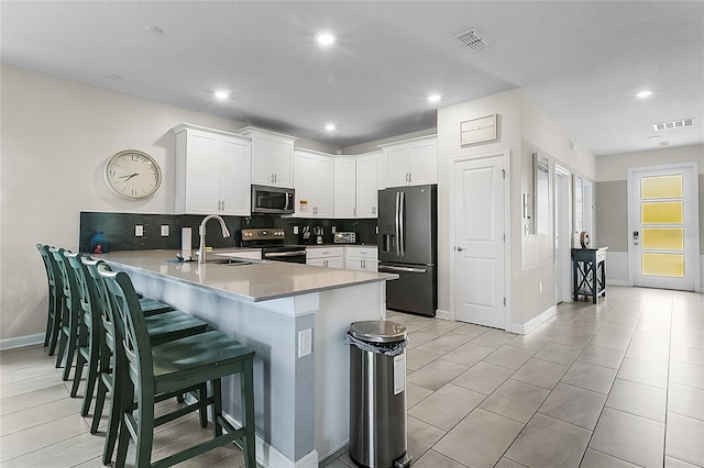 kitchen with white cabinets, tasteful backsplash, stainless steel appliances, and sink