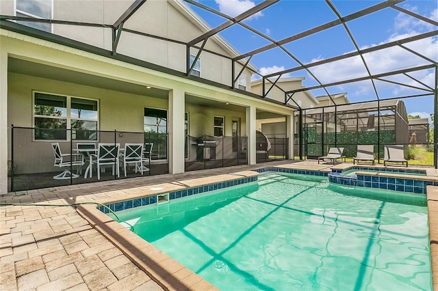 view of pool with an in ground hot tub, glass enclosure, and a patio