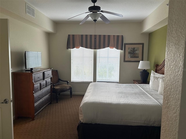 bedroom with ceiling fan, dark carpet, and a textured ceiling