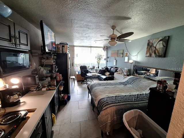 bedroom with ceiling fan, a textured ceiling, light tile flooring, and stainless steel fridge