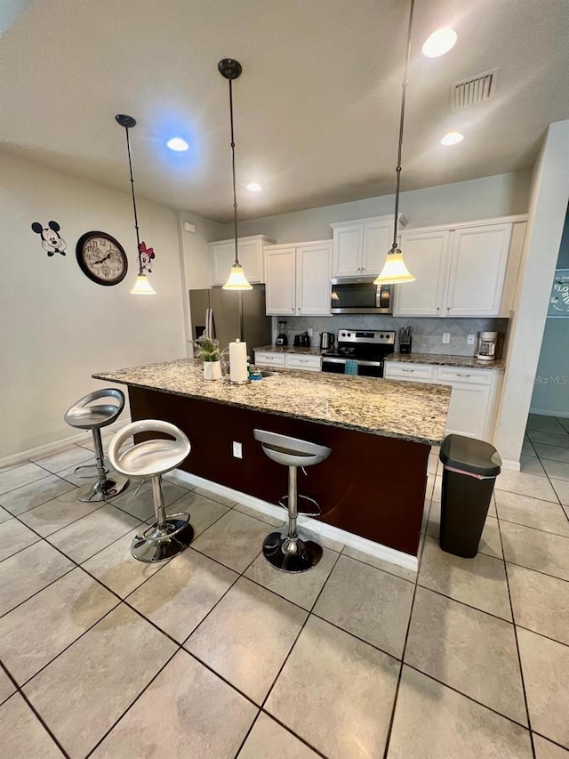 kitchen featuring appliances with stainless steel finishes, a center island with sink, and white cabinets