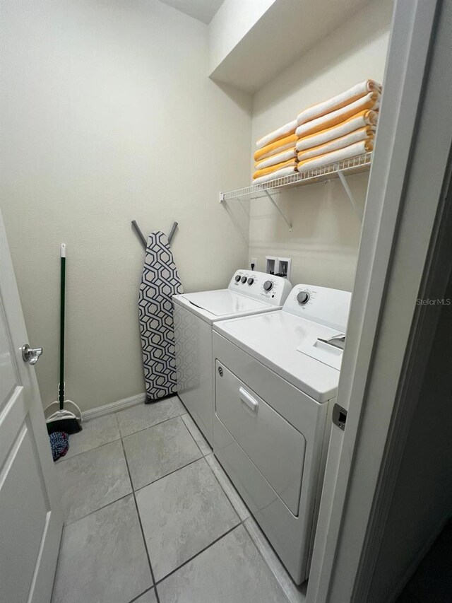 laundry room with hookup for a washing machine, light tile floors, and washer and dryer