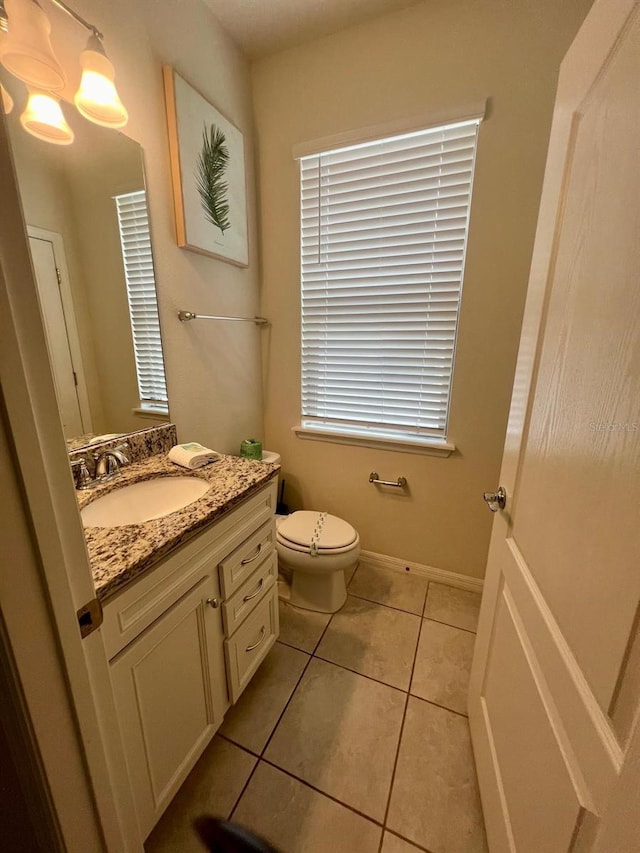 bathroom with toilet, tile flooring, and vanity