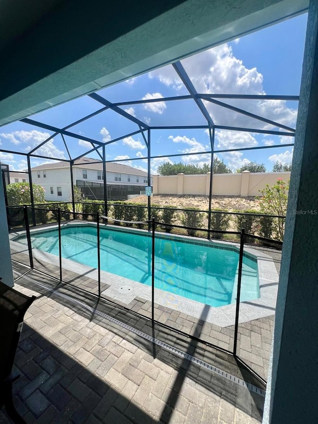 view of swimming pool with glass enclosure and a patio area