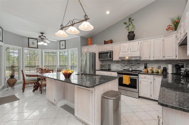 kitchen featuring backsplash, ceiling fan, stainless steel appliances, a center island with sink, and pendant lighting