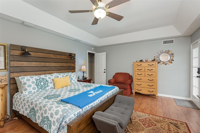 bedroom with a raised ceiling, ceiling fan, and hardwood / wood-style flooring