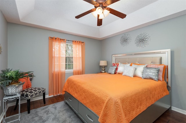 bedroom featuring dark wood-type flooring, ceiling fan, and a raised ceiling