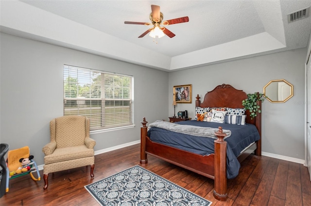 bedroom featuring hardwood / wood-style floors, ceiling fan, a raised ceiling, and a textured ceiling