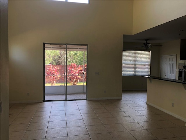 tiled empty room featuring ceiling fan and a wealth of natural light