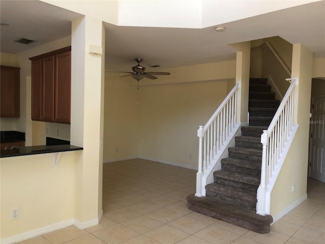 staircase with ceiling fan and tile patterned floors