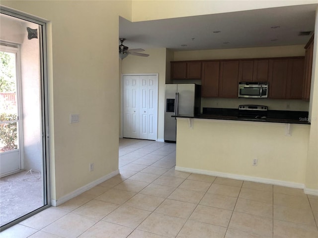 kitchen with ceiling fan, stainless steel appliances, light tile patterned flooring, and kitchen peninsula