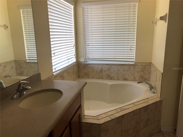 bathroom featuring tiled bath and vanity