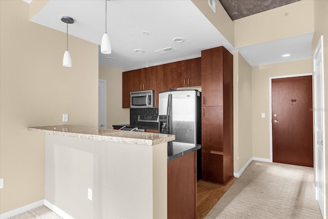 kitchen featuring light stone countertops, kitchen peninsula, appliances with stainless steel finishes, hanging light fixtures, and light carpet