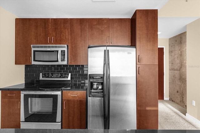 kitchen with backsplash, stainless steel appliances, and dark stone counters