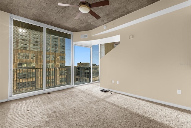 carpeted empty room with expansive windows and ceiling fan