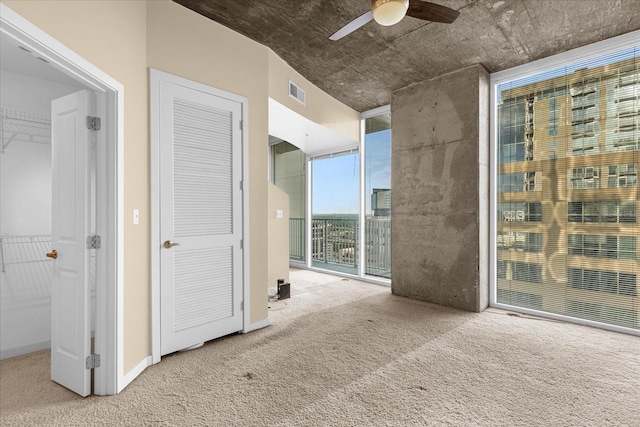 interior space featuring access to outside, carpet flooring, ceiling fan, and floor to ceiling windows