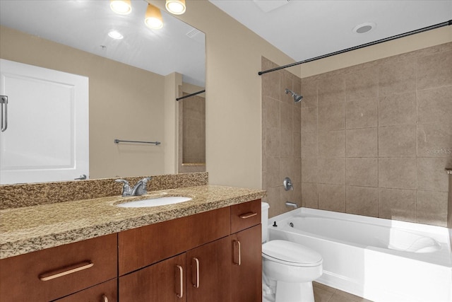 full bathroom featuring tile flooring, vanity, tiled shower / bath combo, and toilet