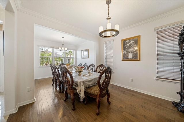 dining area featuring dark hardwood / wood-style flooring, ornamental molding, and an inviting chandelier