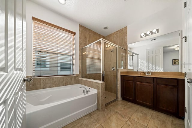 bathroom featuring tile floors, vanity, plus walk in shower, and a textured ceiling