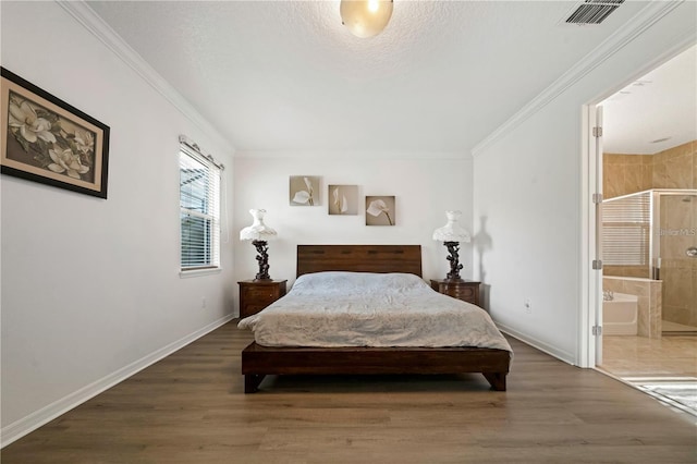 bedroom featuring dark hardwood / wood-style flooring, crown molding, and ensuite bath