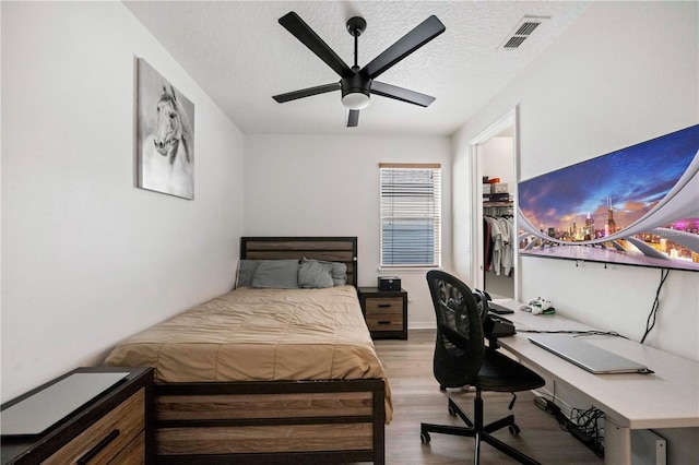 bedroom with ceiling fan, a textured ceiling, and light wood-type flooring