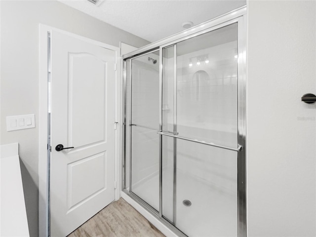 bathroom featuring wood-type flooring and a shower with shower door