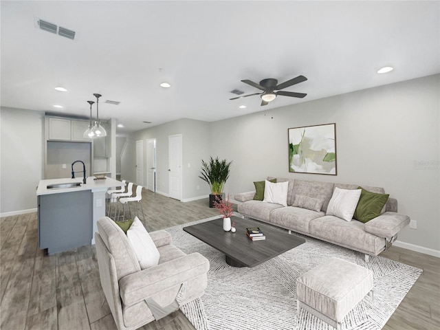 living room with hardwood / wood-style flooring, ceiling fan, and sink