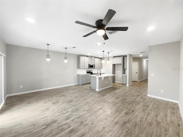 kitchen featuring decorative light fixtures, light hardwood / wood-style flooring, sink, a center island with sink, and ceiling fan