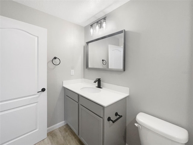 bathroom with wood-type flooring, vanity, and toilet