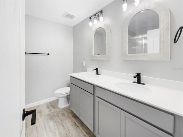 bathroom featuring oversized vanity, hardwood / wood-style floors, toilet, and double sink