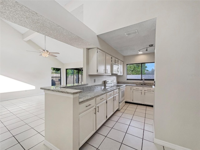 kitchen with kitchen peninsula, white appliances, lofted ceiling, white cabinets, and light tile floors